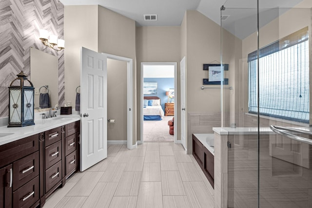 ensuite bathroom featuring a sink, visible vents, double vanity, connected bathroom, and a garden tub