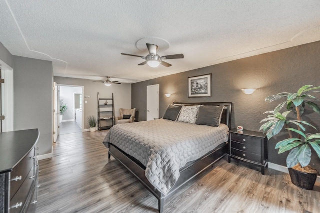 bedroom with baseboards, a textured ceiling, a textured wall, and wood finished floors