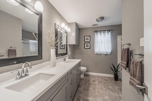 full bath featuring a sink, toilet, a textured ceiling, and visible vents