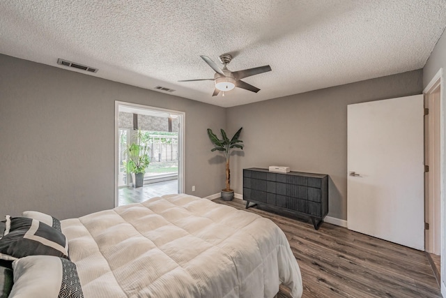 bedroom with visible vents, a textured ceiling, ceiling fan, and wood finished floors