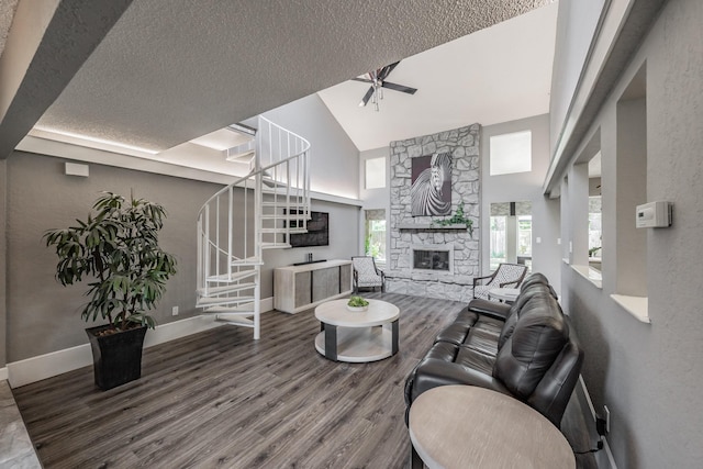 living room with a textured ceiling, a fireplace, wood finished floors, high vaulted ceiling, and stairs