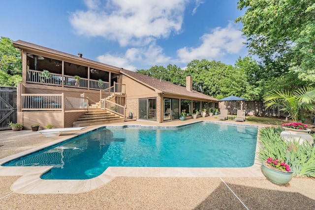 pool with a patio, a fenced backyard, a wooden deck, and stairway