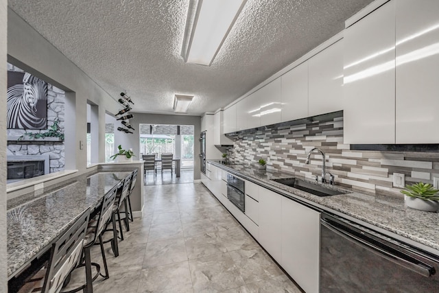 kitchen with a sink, a textured ceiling, black dishwasher, white cabinetry, and modern cabinets