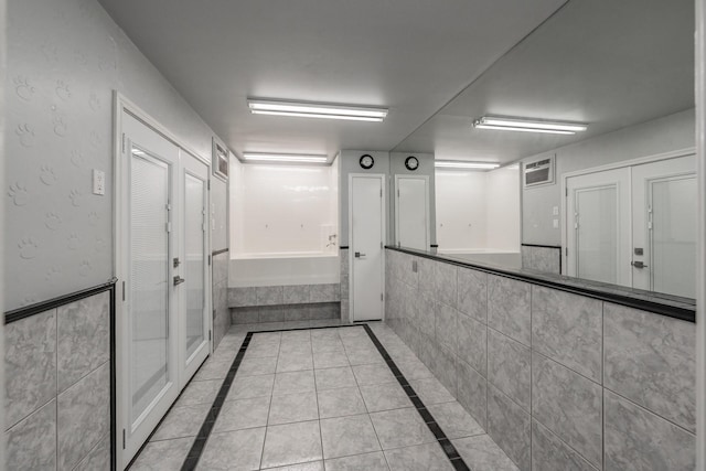 corridor featuring tile patterned flooring and a wainscoted wall