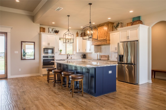 kitchen featuring backsplash, visible vents, appliances with stainless steel finishes, a center island, and white cabinets