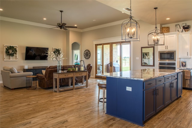 kitchen with visible vents, built in microwave, white cabinets, open floor plan, and oven