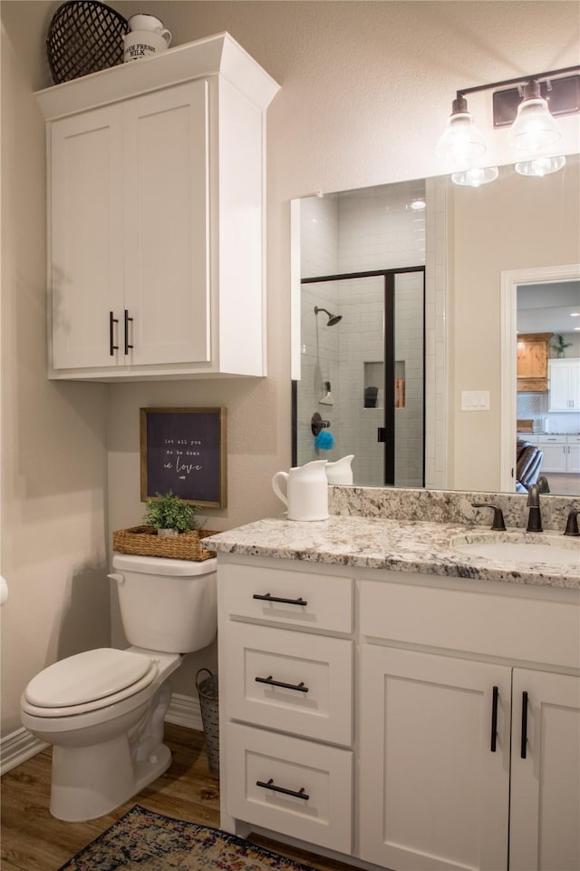 full bath featuring vanity, a stall shower, toilet, and wood finished floors