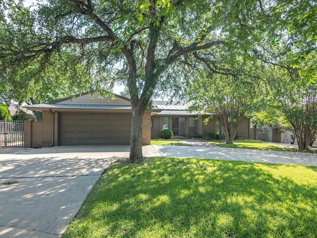 single story home featuring driveway, a front yard, a garage, brick siding, and fence