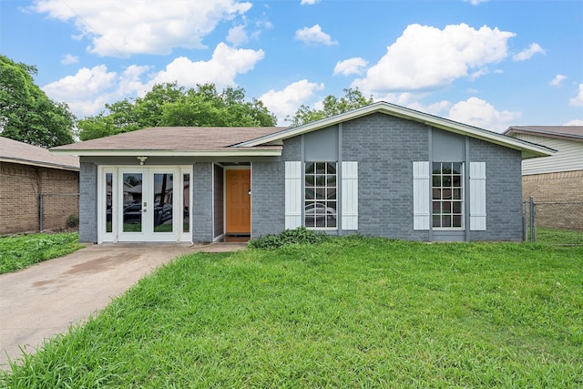 ranch-style home with brick siding, fence, french doors, and a front lawn