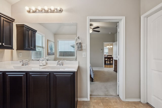 bathroom featuring double vanity, baseboards, a sink, and ceiling fan with notable chandelier
