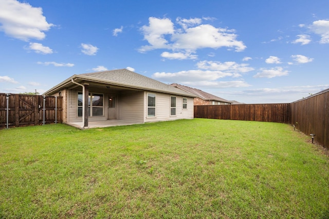 rear view of house featuring a yard, a fenced backyard, and a patio area