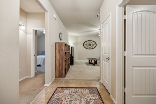 corridor with light tile patterned floors, baseboards, light carpet, and visible vents
