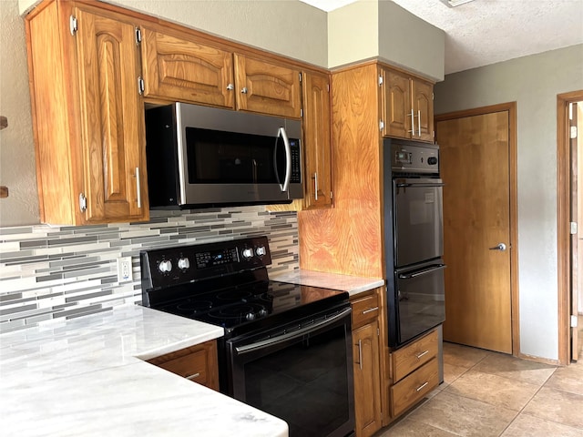 kitchen featuring decorative backsplash, brown cabinetry, black appliances, and a textured ceiling