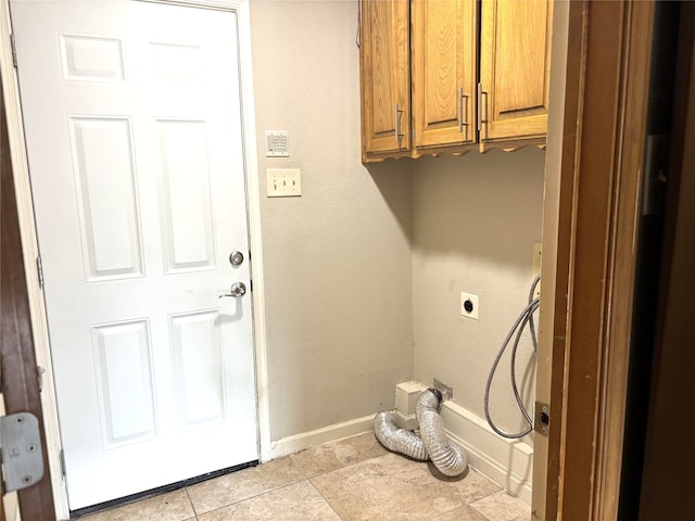 washroom with cabinet space, light tile patterned flooring, hookup for an electric dryer, and baseboards