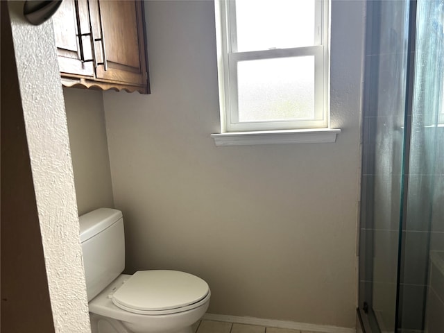 bathroom featuring toilet, a tile shower, and tile patterned flooring