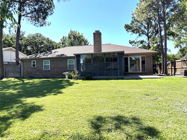rear view of house with brick siding, a fenced backyard, and a chimney