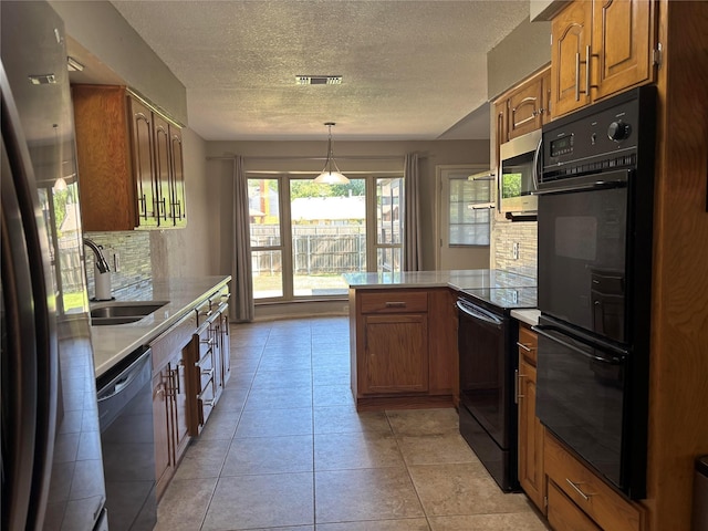 kitchen featuring a sink, brown cabinetry, a peninsula, tasteful backsplash, and black appliances
