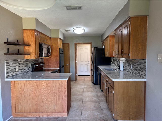 kitchen featuring visible vents, light countertops, a sink, backsplash, and black appliances