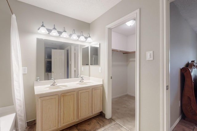 3073 Dusty Ridge Dr, Rockwall, TX 75032 - full bathroom featuring double vanity, a textured ceiling, a sink, and a walk in closet
