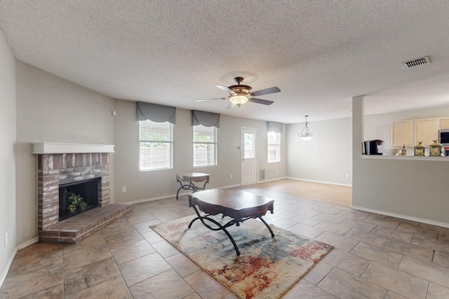 3073 Dusty Ridge Dr, Rockwall, TX 75032 - living area featuring visible vents, a brick fireplace, ceiling fan, a textured ceiling, and light tile patterned floors