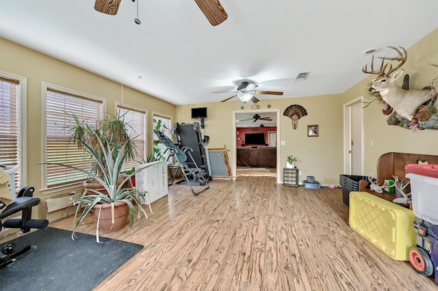 exercise area featuring visible vents, ceiling fan, and wood finished floors