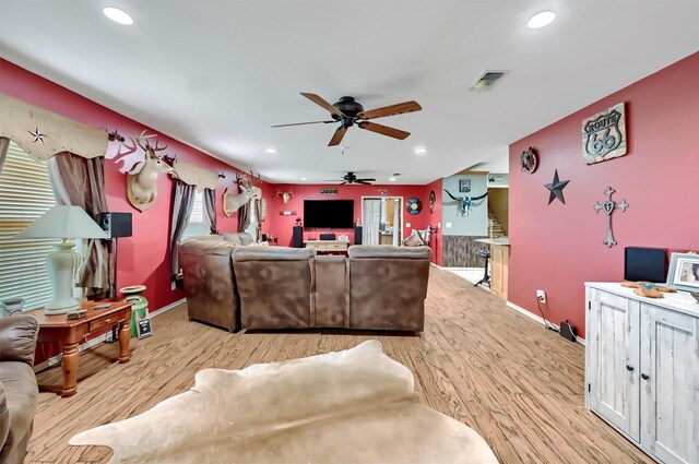 living area with visible vents, a ceiling fan, baseboards, and light wood-style floors