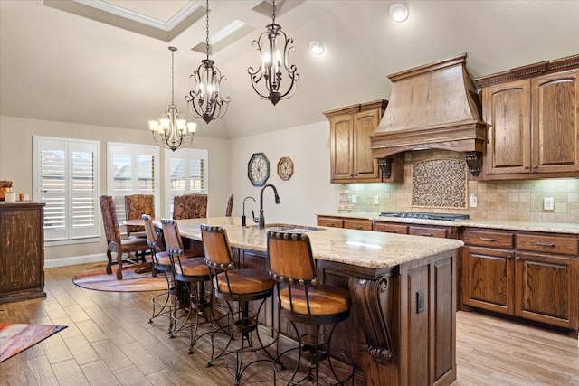 1408 Joshua Way, Granbury, TX 76048 - kitchen with a kitchen island with sink, custom exhaust hood, a kitchen breakfast bar, a chandelier, and a sink