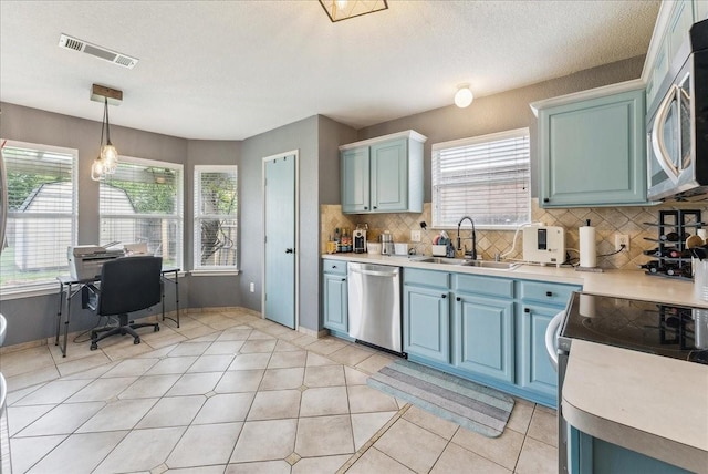 kitchen featuring visible vents, a sink, appliances with stainless steel finishes, and blue cabinets