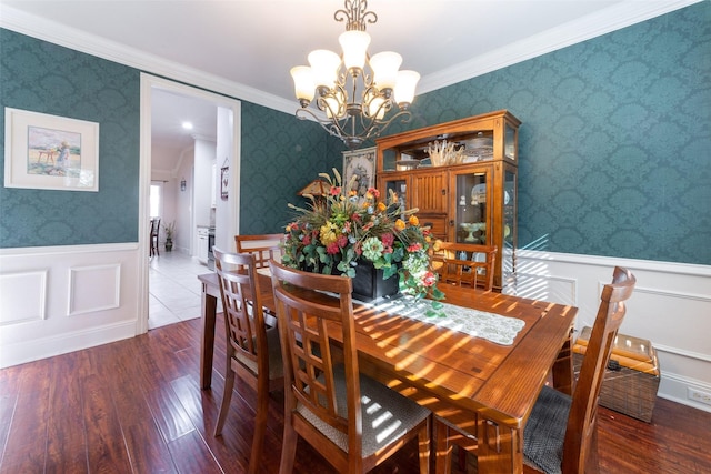 dining area featuring wallpapered walls, an inviting chandelier, wood finished floors, and a wainscoted wall