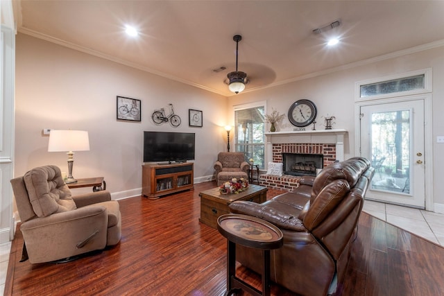 living room with baseboards, ornamental molding, a fireplace, and wood finished floors