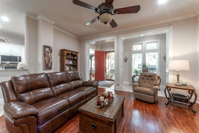 living area with crown molding, a ceiling fan, baseboards, and hardwood / wood-style flooring