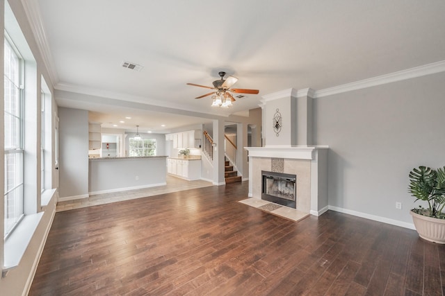unfurnished living room featuring crown molding, a ceiling fan, visible vents, and wood finished floors