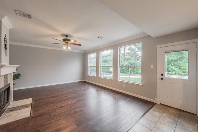 unfurnished living room featuring a ceiling fan, visible vents, a tiled fireplace, baseboards, and hardwood / wood-style floors