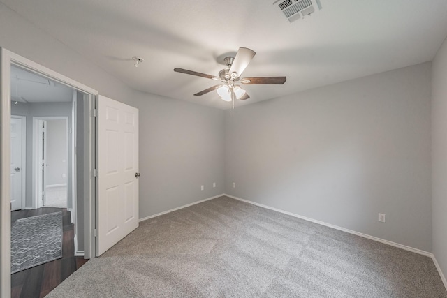 carpeted spare room featuring ceiling fan, visible vents, and baseboards
