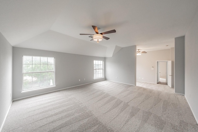 empty room with baseboards, light carpet, a ceiling fan, and lofted ceiling