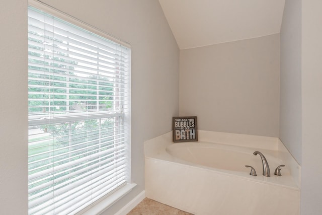 bathroom with tile patterned flooring, vaulted ceiling, and a garden tub