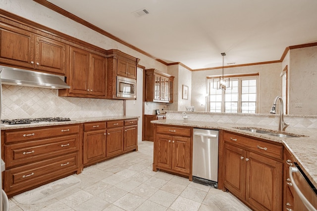 kitchen with brown cabinetry, a sink, under cabinet range hood, and stainless steel appliances
