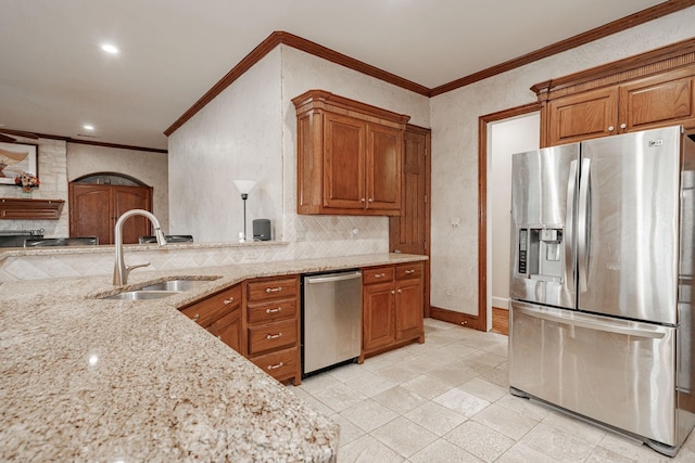 kitchen with crown molding, appliances with stainless steel finishes, light stone counters, a sink, and brown cabinetry
