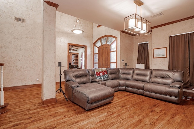living room with a textured wall, visible vents, and light wood-style floors