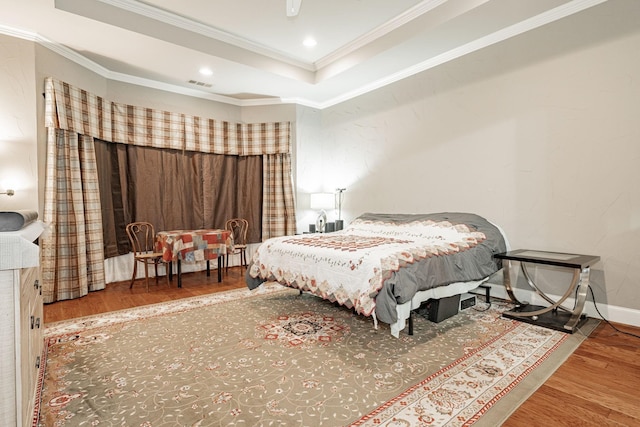 bedroom featuring crown molding, visible vents, wood finished floors, recessed lighting, and a raised ceiling