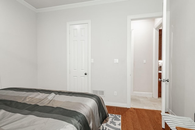 bedroom featuring crown molding, baseboards, visible vents, and wood finished floors