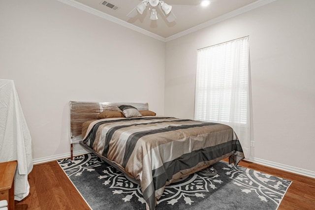 bedroom featuring visible vents, ornamental molding, baseboards, and wood finished floors