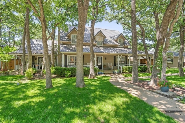 view of front facade with fence, a porch, a front yard, a standing seam roof, and metal roof