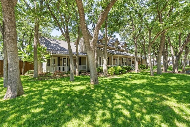 view of front facade with a porch, a front lawn, fence, and metal roof