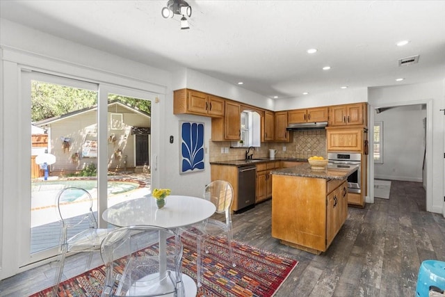 kitchen featuring visible vents, dark wood-type flooring, a center island, a sink, and appliances with stainless steel finishes