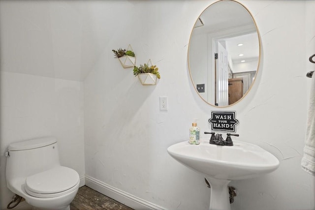 half bathroom with baseboards and toilet