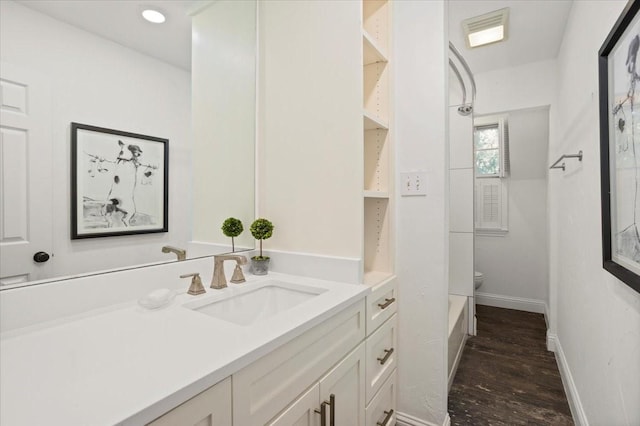 bathroom featuring visible vents, wood finished floors, vanity, baseboards, and toilet