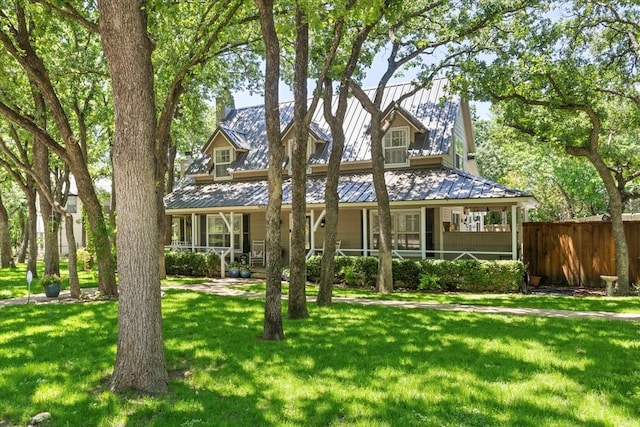 view of front of property featuring a standing seam roof, fence, a porch, and a front lawn