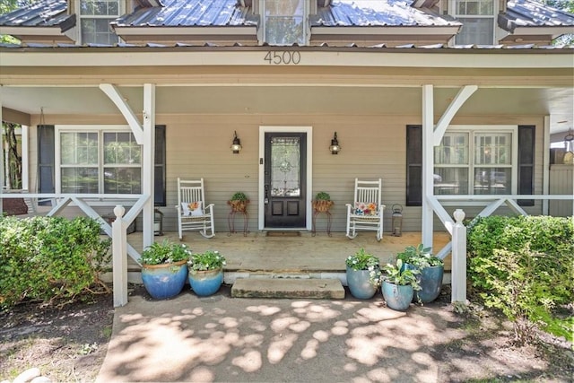view of exterior entry featuring a porch and metal roof