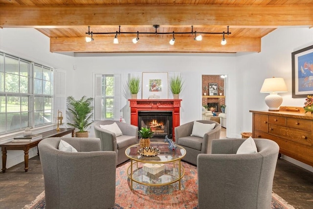 living area featuring wood ceiling, beamed ceiling, a lit fireplace, and rail lighting